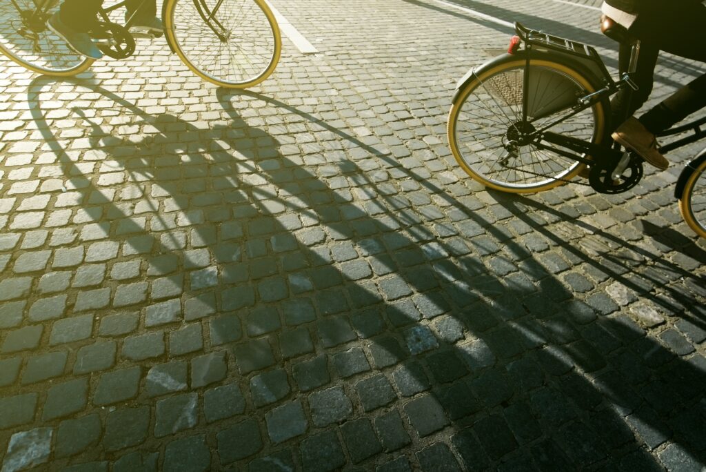 City cyclists, people riding bicycles on cobblestone road