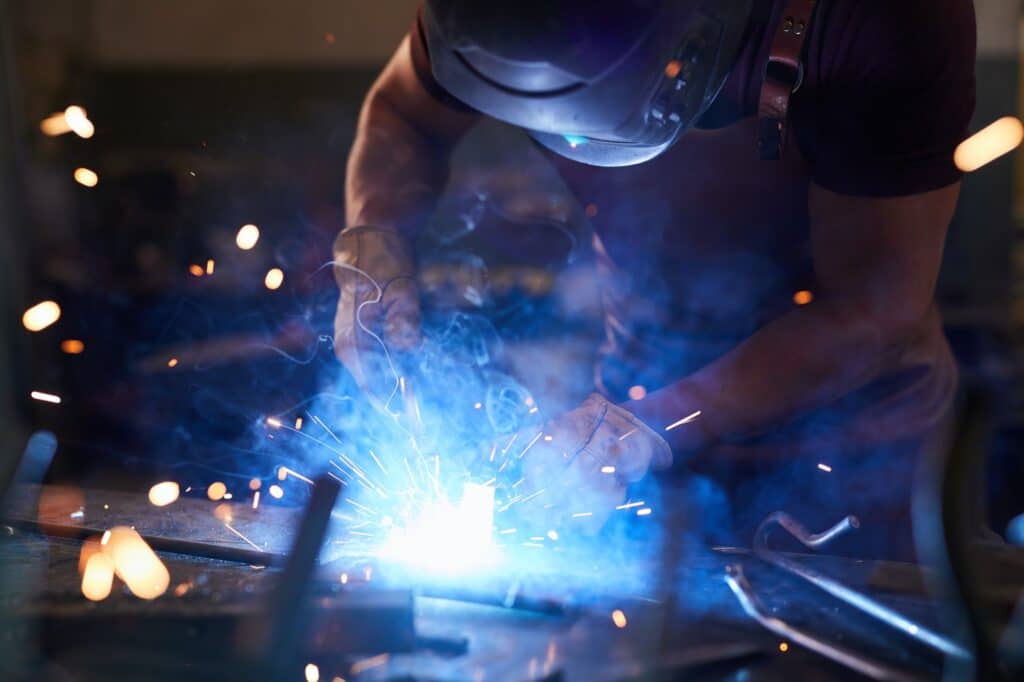 Laborer melting metal with welding tool