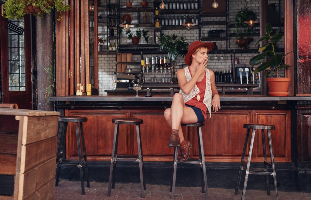 Young woman with hat smoking in a bar